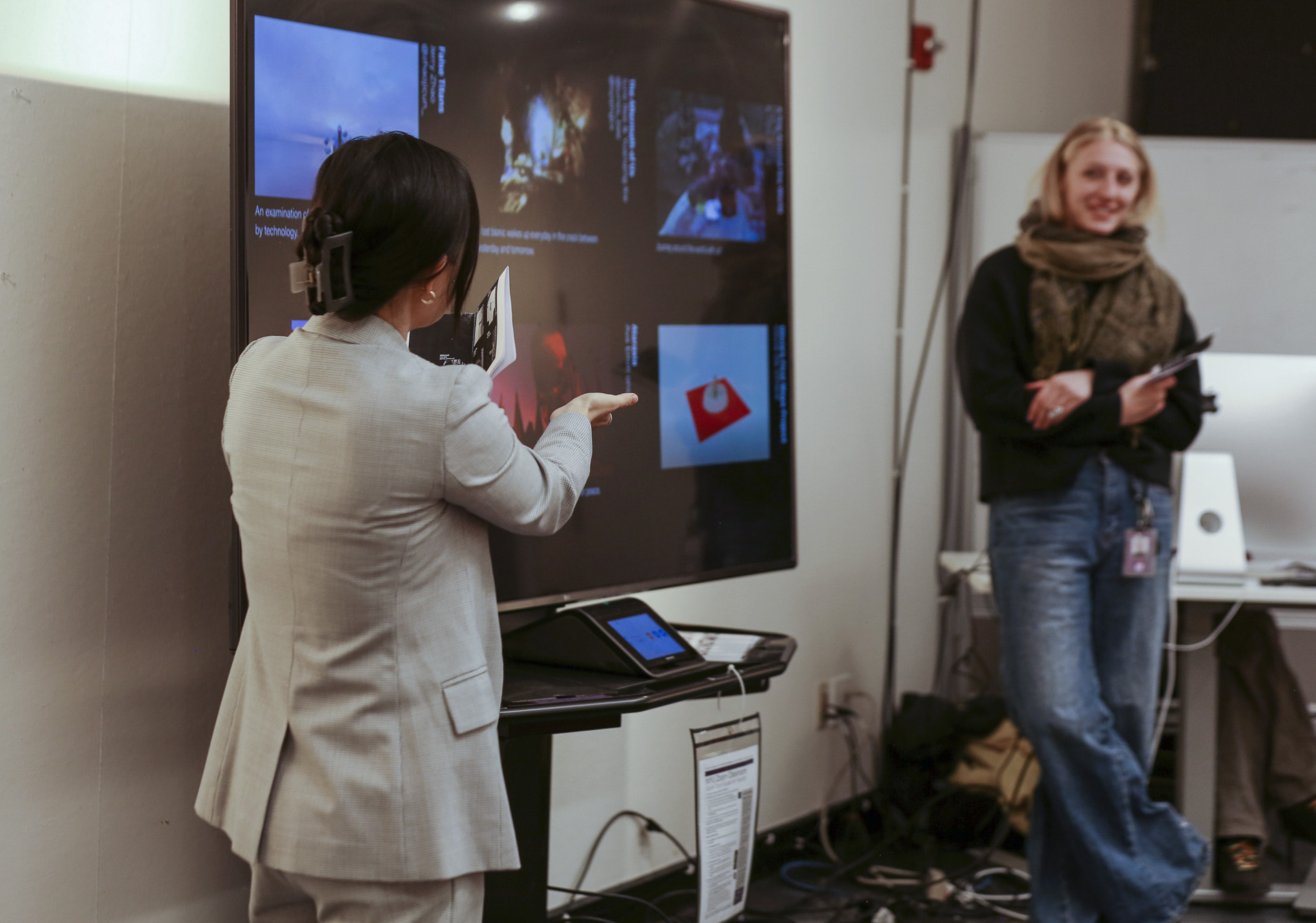 Professor Snow Fu and student Cora Rafe both stand near a television